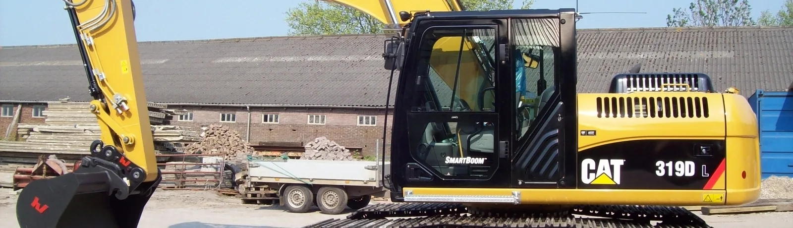 Gele Caterpillar 319D L rupsgraafmachine op een terrein